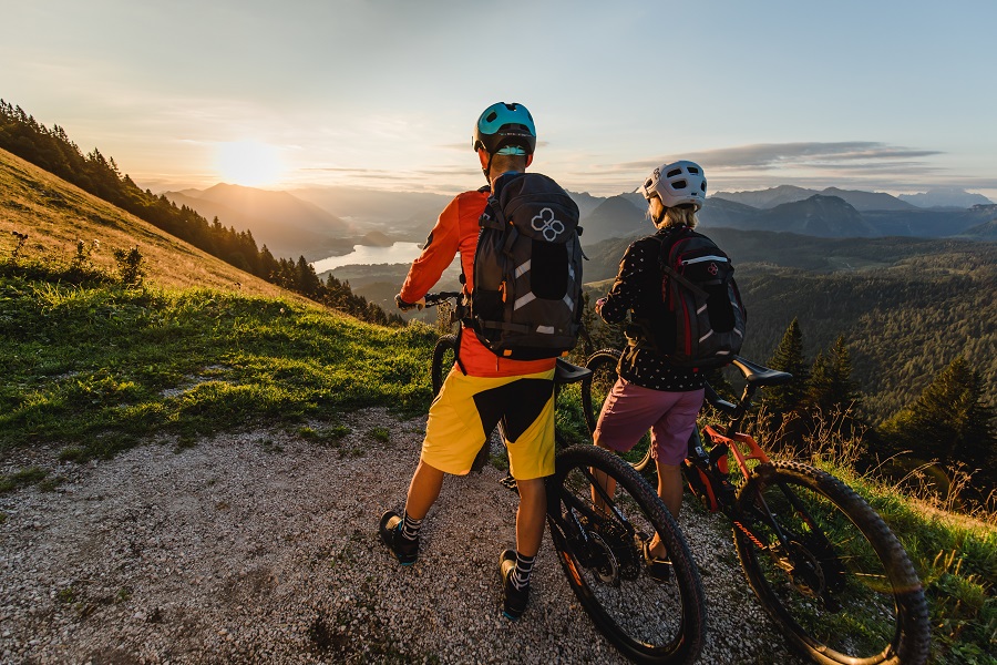 Zwei Mountainbiker auf dem BergeSeen eTrail der 6 Seen Tour in der Fuschlseeregion genießen den Sonnenuntergang mit herrlichem Bergpanorama